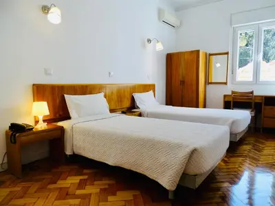 a hotel room with two beds and a window at Poveira Hotel in Porto