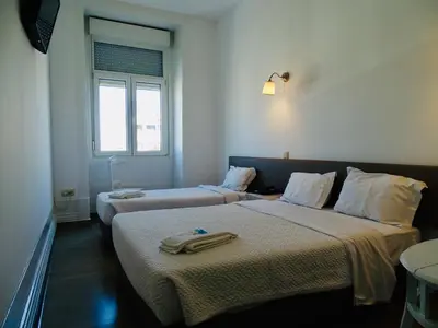 a hotel room with two beds and a window at Poveira Hotel in Porto