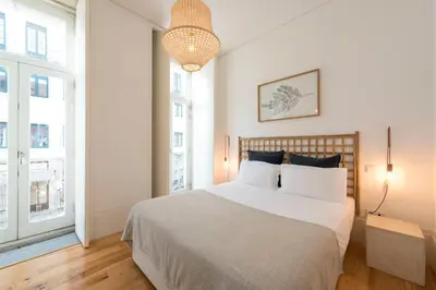a white bedroom with a large bed and two windows at Light Blue Apartment in Porto
