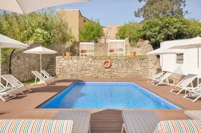 a swimming pool with chairs and a stone wall at UMA Santa Catarina - Pool & Fitness, Adults Only in Porto