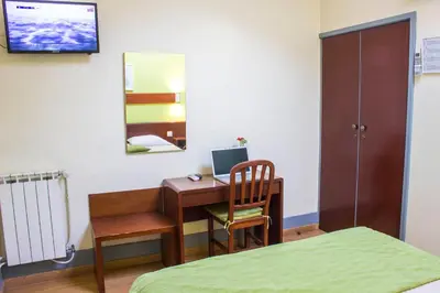 a bedroom with a desk with a computer and a bed at Hotel Estoril Porto in Porto