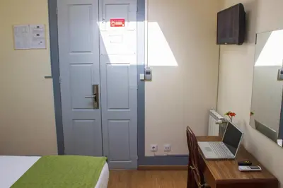 a room with a bed and a desk with a laptop at Hotel Estoril Porto in Porto