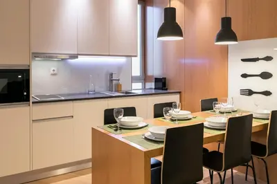 a kitchen with a dining table with chairs and a kitchen with white cabinets at Oportments - Oliveiras in Porto