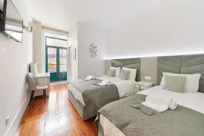 a hotel room with two beds and a window at A Portuguesa Guest House in Porto