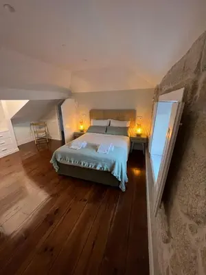 a bedroom with a large bed and a wooden floor at A Portuguesa Guest House in Porto