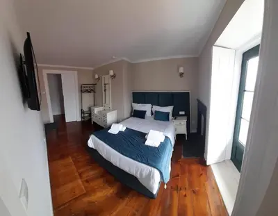 a bedroom with a large bed with blue sheets and pillows at A Portuguesa Guest House in Porto