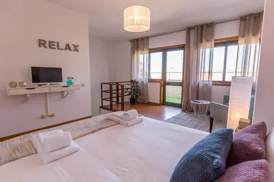 a bedroom with a large white bed and a television at Sunset Relaxing Apt with terrace, parking & bikes in Porto