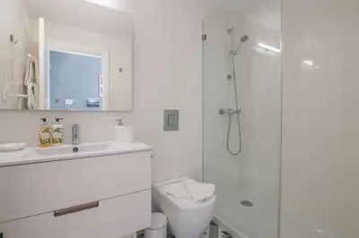 a white bathroom with a shower and a toilet at Central location with garden & equipped kitchen in Porto