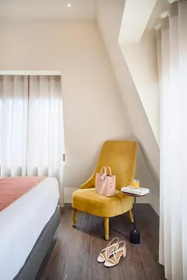 a bedroom with a bed and a yellow chair and a table at Hotel Moon & Sun Porto in Porto