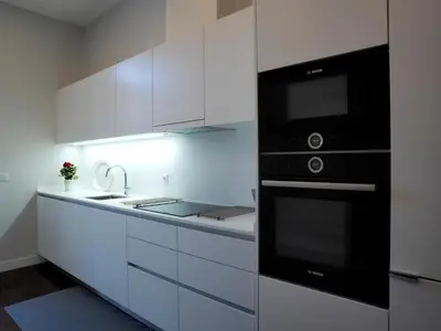 a kitchen with white cabinets and a black appliance at Cool Terrace Apartment in Porto