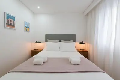 a white bedroom with a large bed with two lamps at Bruno's Downtown Apartment in Porto