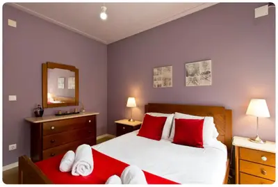 a bedroom with a bed with red pillows and a mirror at Porto Village Inn in Porto