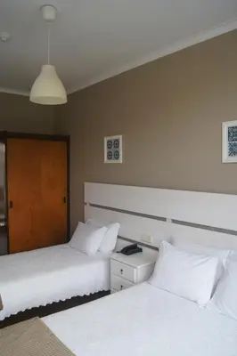 two beds with white pillows in a room at Hotel Chique Aliados in Porto