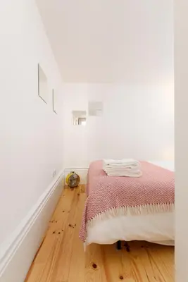 a white room with a bed and a wooden floor at Skylight Apartment in Porto