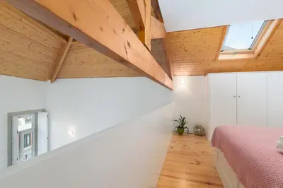 a bedroom with white walls and wooden ceilings at Skylight Apartment in Porto