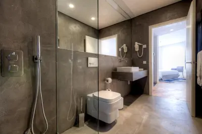 a bathroom with a toilet and a glass shower at InPatio Guest House in Porto