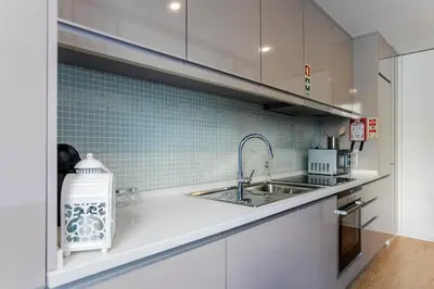 a kitchen with white cabinets and a sink at Chillout Trindade Apartment in Porto