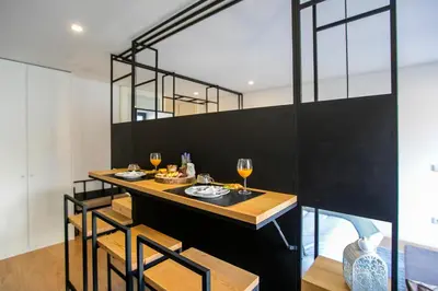 a dining room with a bar with chairs and wine glasses at Chillout Trindade Apartment in Porto