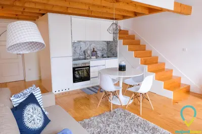 a living room with a staircase and a table and chairs at Loft Almada in Porto