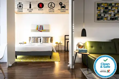 a bedroom with a bed and a green couch at PortoSoul Trindade in Porto
