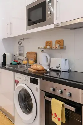 a kitchen with a washing machine and a microwave at Central Apartamento 0 AC Metro Nearby in Porto
