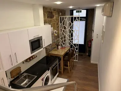 a kitchen with white cabinets and a table with a microwave at Central Apartamento 0 AC Metro Nearby in Porto
