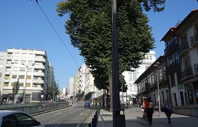 two people walking down a city street with a pole at Ceuta Inn Porto in Porto