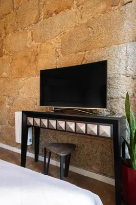 a black table with a television on a brick wall at Central Cozy Star 1 Balcony AC Near Merto in Porto
