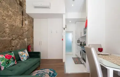 a living room with a green couch and a kitchen at Central Cozy Stay 2 AC Near Metro in Porto