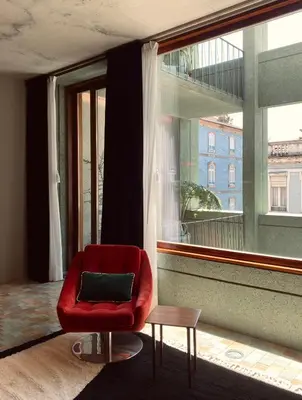 a red chair sitting in front of a large window at Hotel Tipografia do Conto by Casa do Conto in Porto