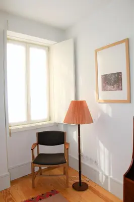 a chair and a lamp in a room with windows at Amazing City Center Apartment Porto Villa Lóios in Porto