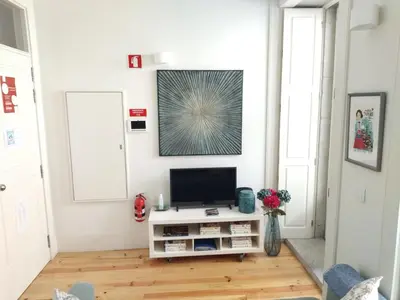 a living room with a tv on a white wall at Santa Catarina Patio Apartment - with washer machine in Porto