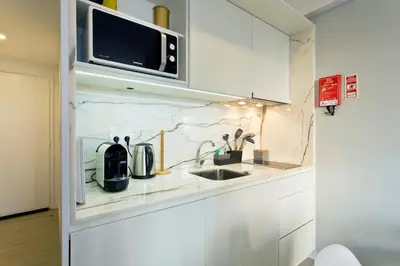 a white kitchen with a sink and a microwave at Downtown Porto Spot in Porto