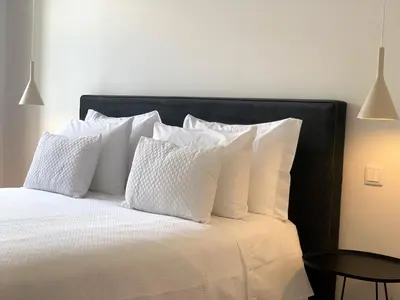 a bedroom with a white bed with white pillows at RIBEIRA OPORTO APARTMENT (NEW) in Porto