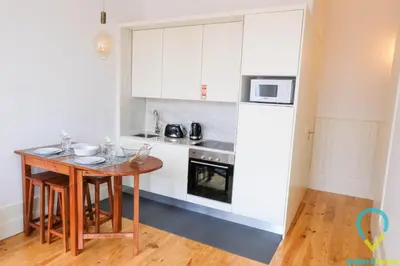 a kitchen with white cabinets and a wooden table at Simply Porto in Porto