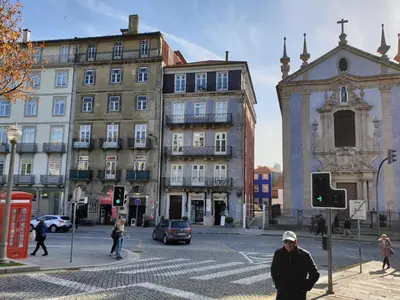 a man crossing a street in a city with buildings at Lux Ribeira - ALL INCLUDED in Porto