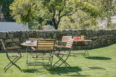 a table and chairs in the grass near a stone wall at Liiiving In Porto | Downtown Luxury Apartments in Porto