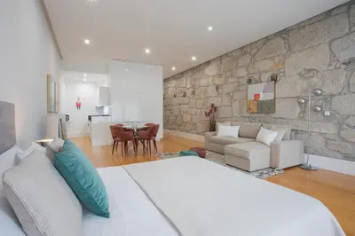 a bedroom with a white bed and a stone wall at Liiiving In Porto | Downtown Luxury Apartments in Porto
