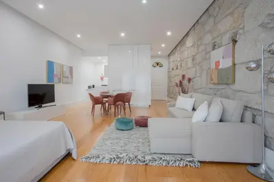 a living room with white furniture and a stone wall at Liiiving In Porto | Downtown Luxury Apartments in Porto