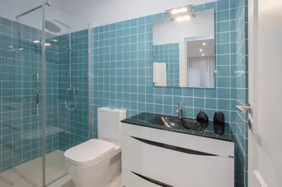 a blue tiled bathroom with a toilet and a sink at Liiiving In Porto | Downtown Luxury Apartments in Porto