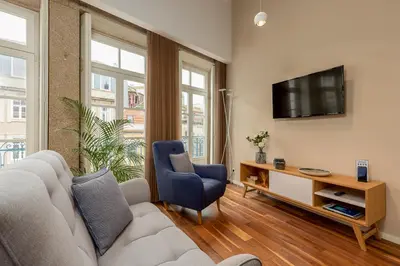 a living room with a couch and a tv on a wall at RS Porto Historic Center in Porto