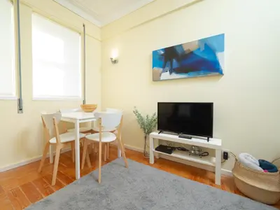 a living room with a table and a tv at Oporto Guest Alegria Flat Downtown in Porto