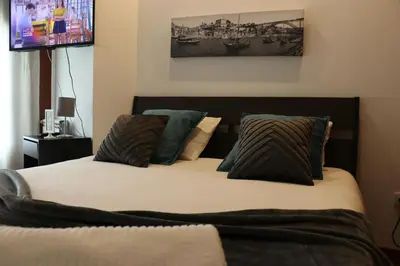 two twin beds in a room with a tv at Metro Heroismo Residence in Porto