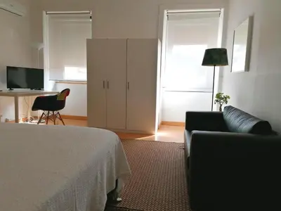 a living room with a bed and a couch and a desk at Downtown Porto Spot - 2 bedrooms in Porto