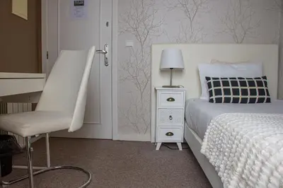 a white bedroom with a bed and a chair at O'Porto Seven - Guest House in Porto