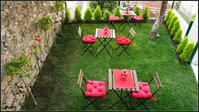 a group of tables and chairs with red seats on the grass at Hostel Gaia Porto in Vila Nova de Gaia