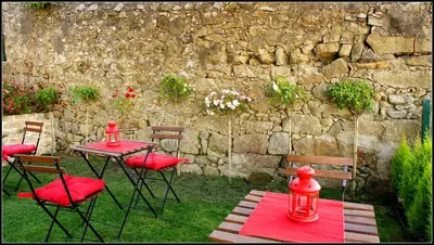 a table with red chairs and a stone wall at Hostel Gaia Porto in Vila Nova de Gaia