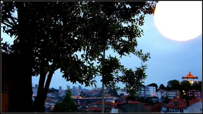 a full moon rising over a city at night at Hostel Gaia Porto in Vila Nova de Gaia