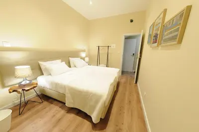 a bedroom with a large white bed and a lamp at Naya-Downtown Guesthouse in Porto