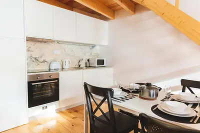 a kitchen with a table with chairs and a stove at Aposentus -Romantic Mezzanine Apartment With a Balcony in Porto